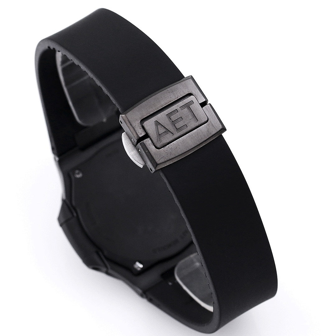 Black rubber watch strap with metal clasp and embossed AET detail near the buckle.