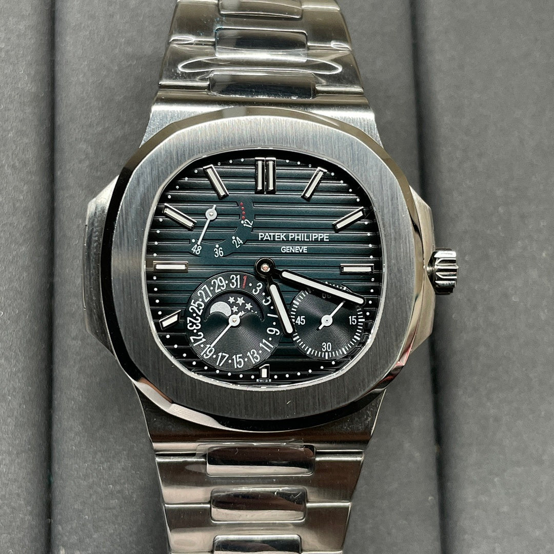 Stainless steel luxury wristwatch with dark dial, teal accents, and metal bracelet