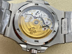 Patek Philippe watch caseback with gold-toned movement and steel bracelet links