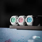Three white sport watches on a stand with green, pink, and light blue dials