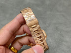Gold-tone Patek Philippe watch bracelet detail with clasp and folded links.