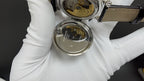 Patek Philippe watch with open case showing gold-toned movement under glass