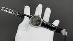 Patek Philippe wristwatch on black leather strap, side view of black dial