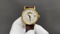 Patek Philippe watch with gold case, white dial, brown leather strap and date window
