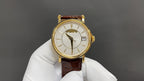 Patek Philippe watch with gold case, white dial, brown leather strap and date window