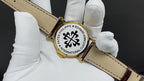 Patek Philippe watch on brown leather strap with caseback emblem and gold buckle