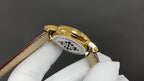 Patek Philippe watch caseback with gold finish and engraved emblem on brown strap