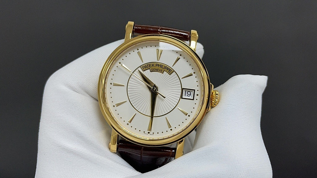 Patek Philippe watch front view with gold bezel, white dial and brown leather strap