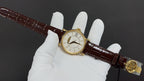Patek Philippe watch on brown leather strap held in white gloves