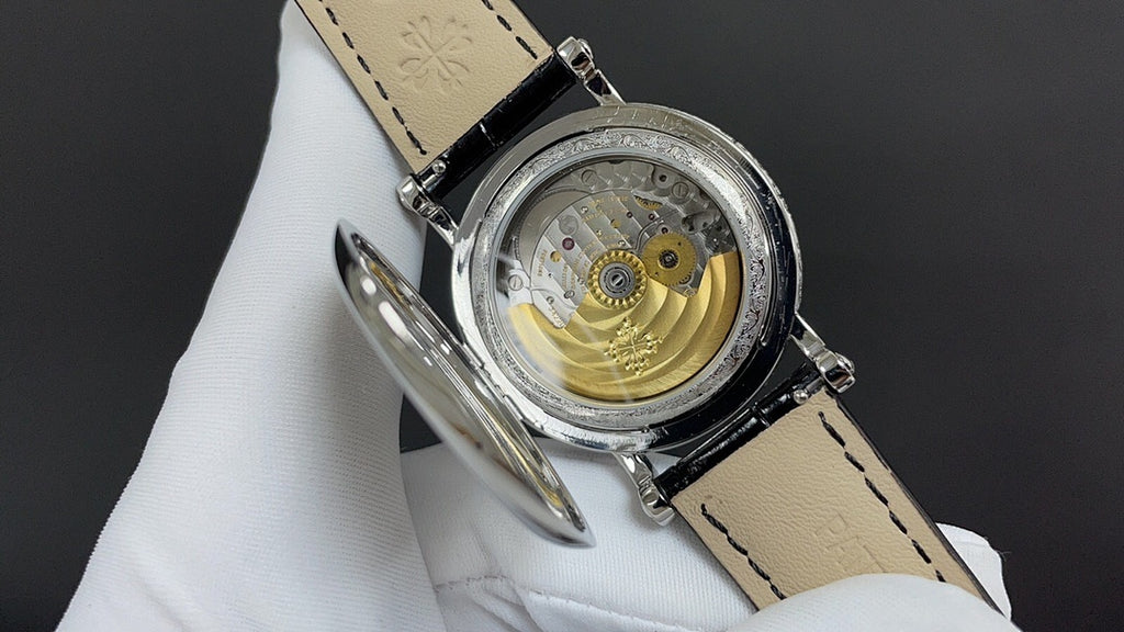 Wristwatch movement view with gold balance wheel and black leather strap
