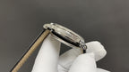 Wristwatch side view with crown and polished silver case on leather strap
