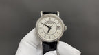 Wristwatch with silver bezel, white dial, black leather strap and date window