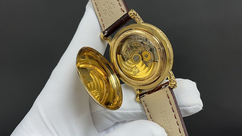 Patek Philippe wristwatch with open case back, gold-tone parts and brown leather strap