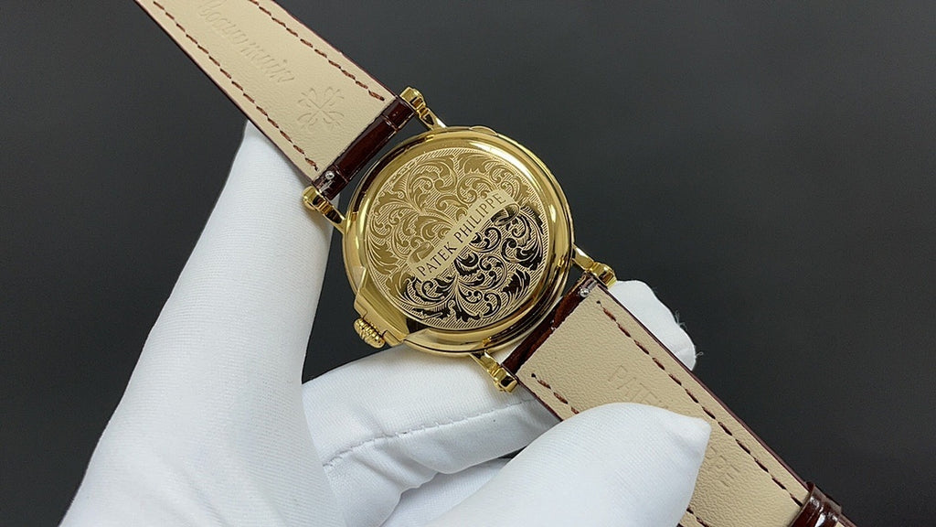 Patek Philippe wristwatch with engraved gold-tone case back and brown leather strap