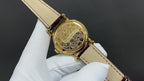 Patek Philippe wristwatch with engraved gold-tone case back and brown leather strap