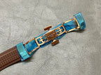 Brown leather watch strap with blue clasp and gold-toned clasp hardware