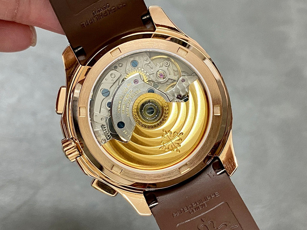 Patek Philippe watch case back with exposed gold-toned movement and brown strap