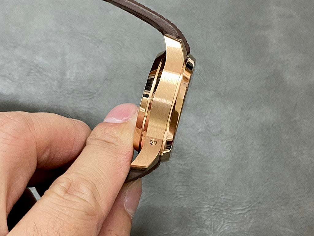 Gold-toned watch side profile with crown and brown leather strap