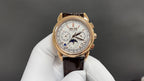 Gold-tone luxury wristwatch with white dial and brown leather strap, front view