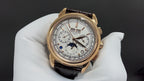Gold-tone luxury wristwatch with white dial, subdials, and brown leather strap