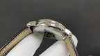 Wristwatch case with reflective bezel and tan leather strap, side profile view