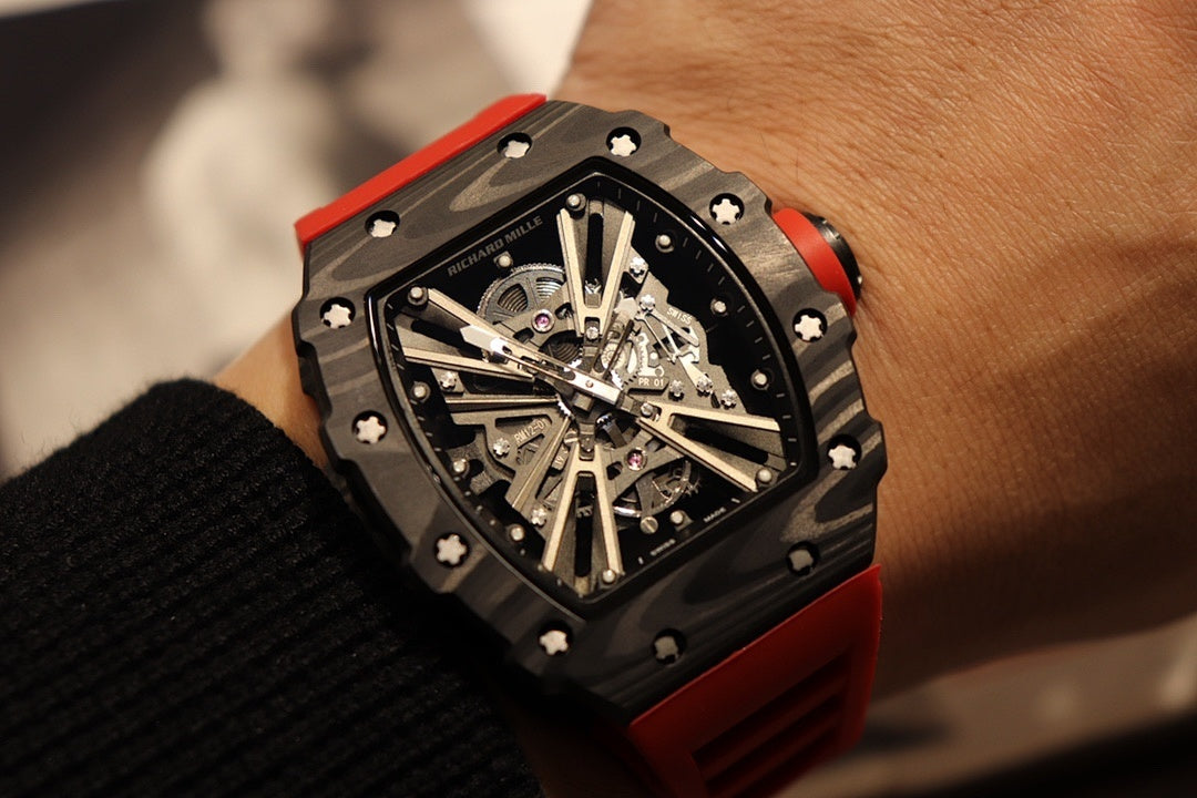 Richard Mille watch with black bezel, skeletal dial, and red strap on wrist