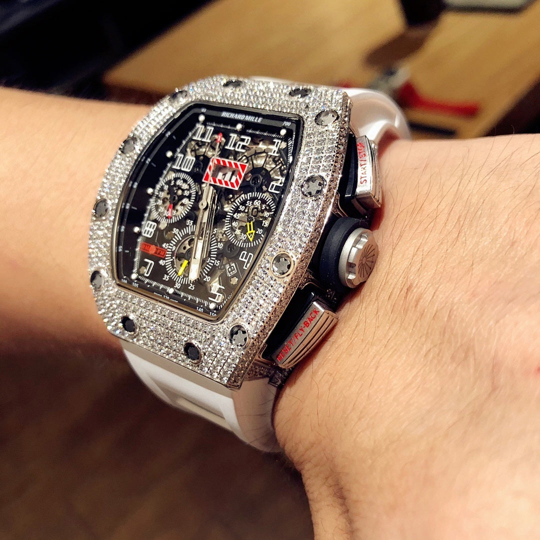 Square luxury watch close side view on wrist, jeweled case and white rubber strap