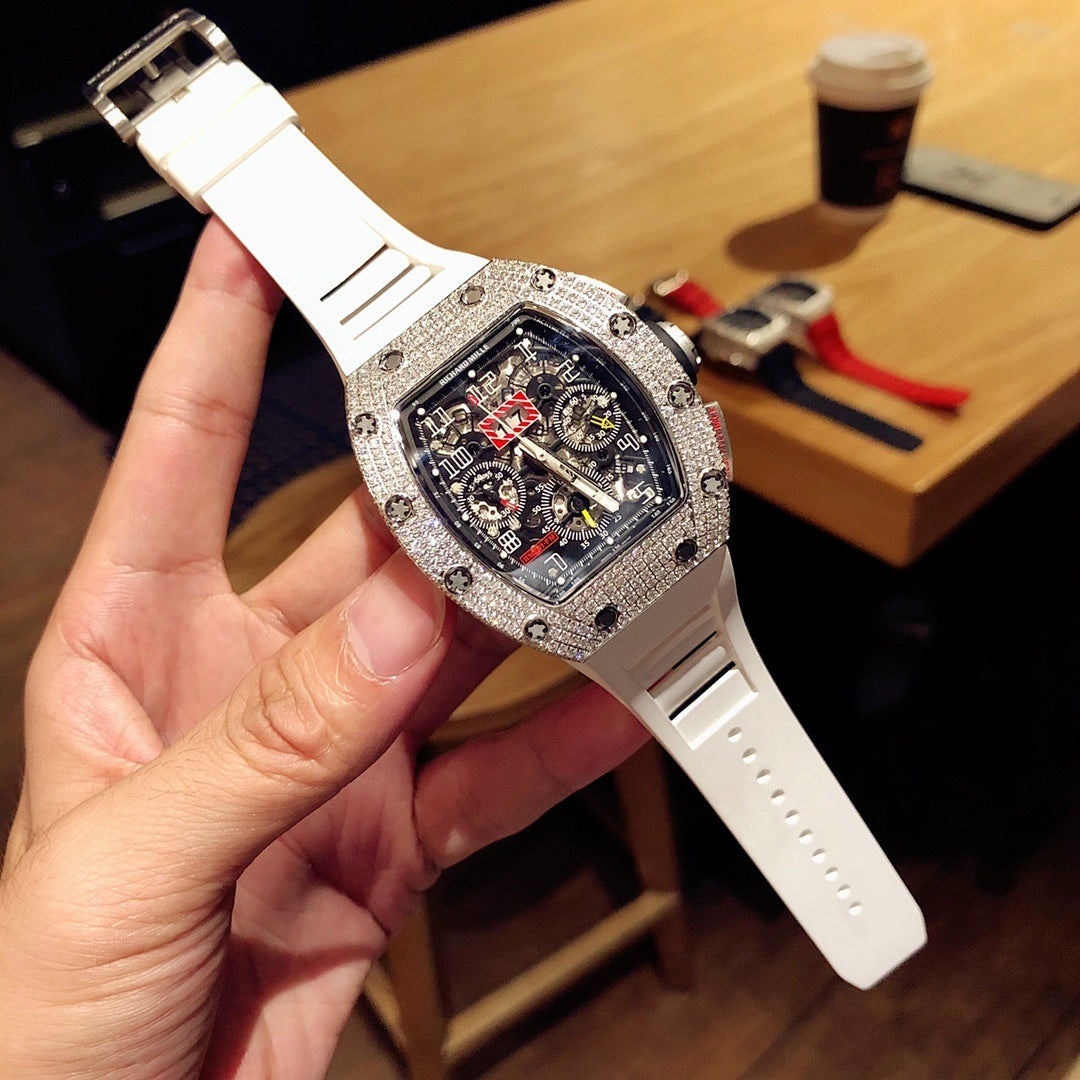 Square luxury watch with dark blue dial, jeweled bezel, and white rubber strap