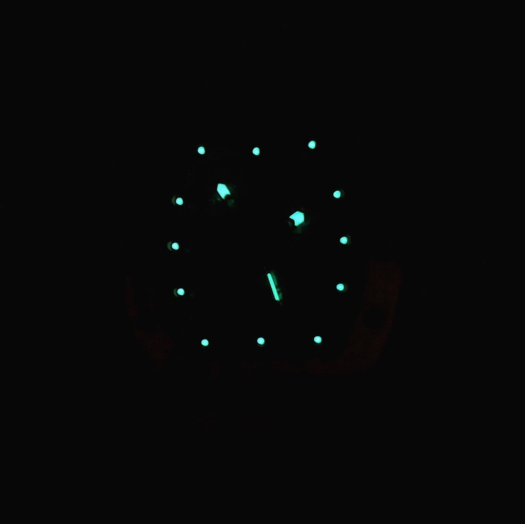Watch dial with green glowing markers on a dark background