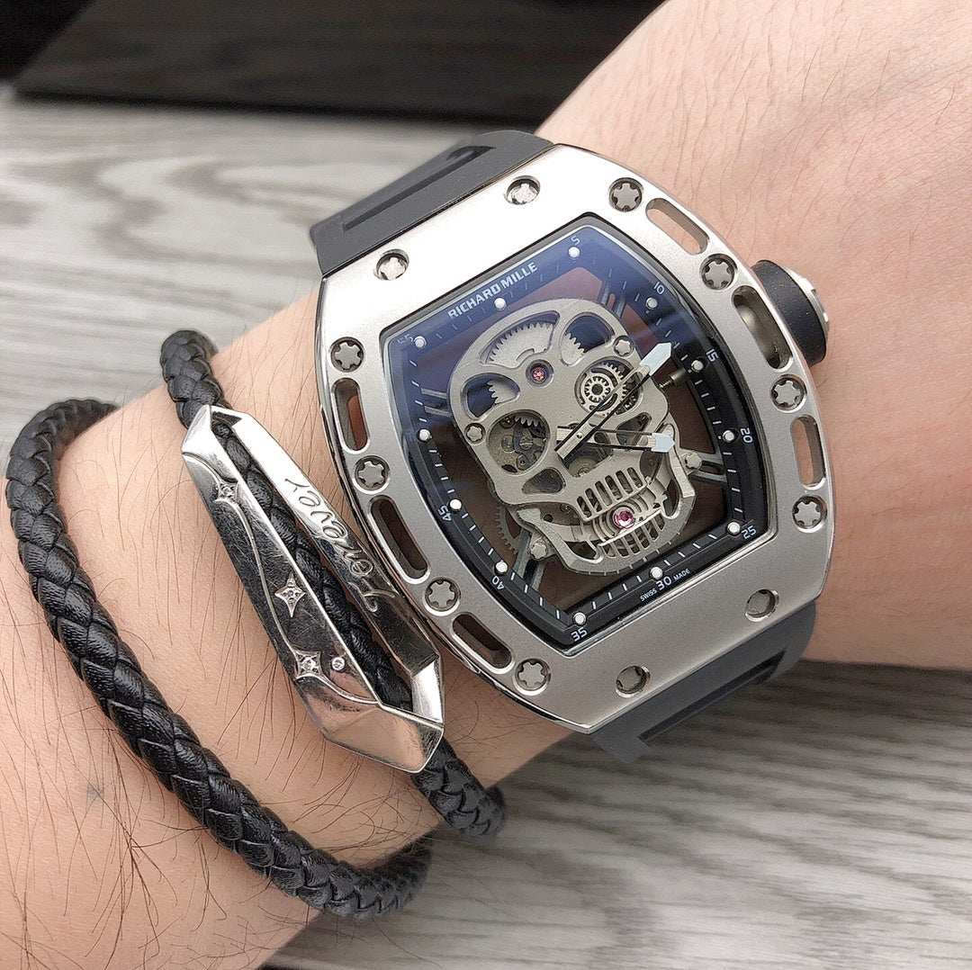 Skeleton watch with silver case and black strap worn on wrist, exposed gears visible
