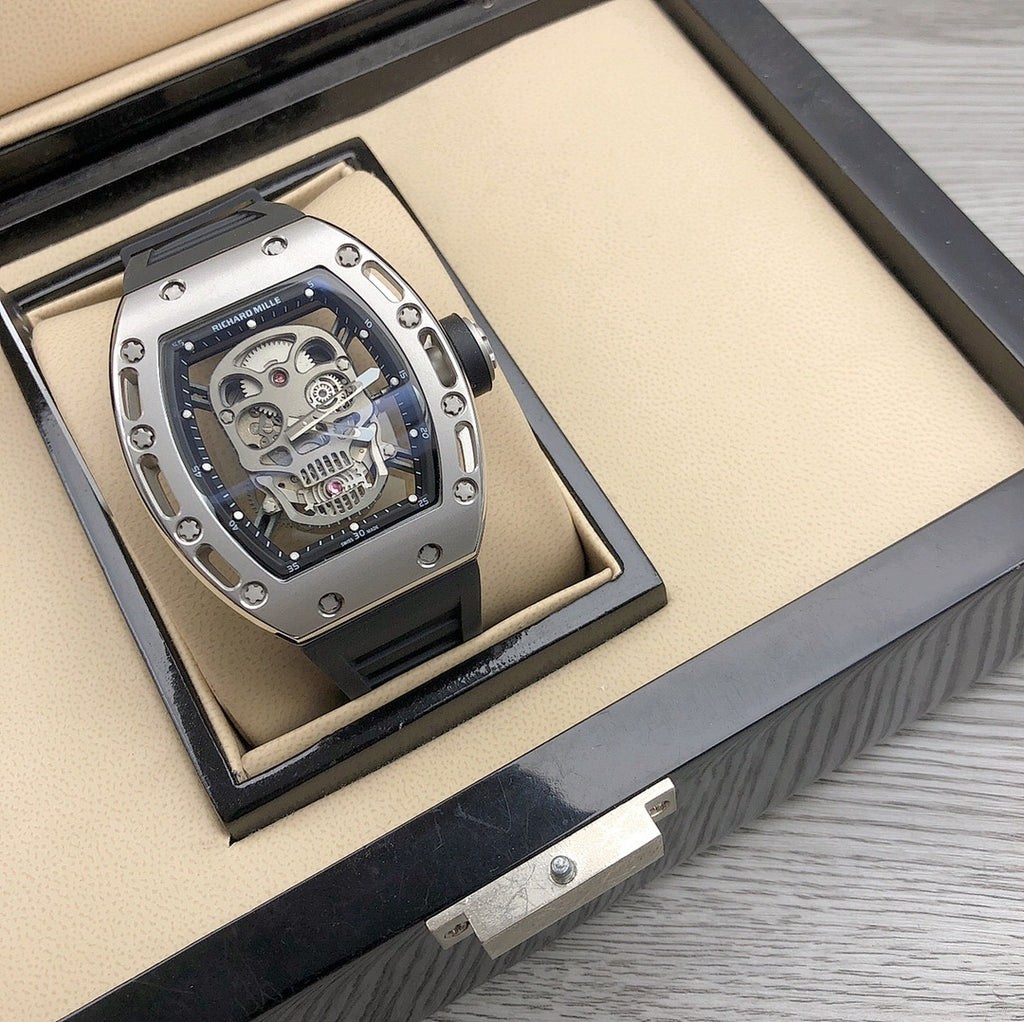 Skeleton sport watch in open display box, silver case and black rubber strap
