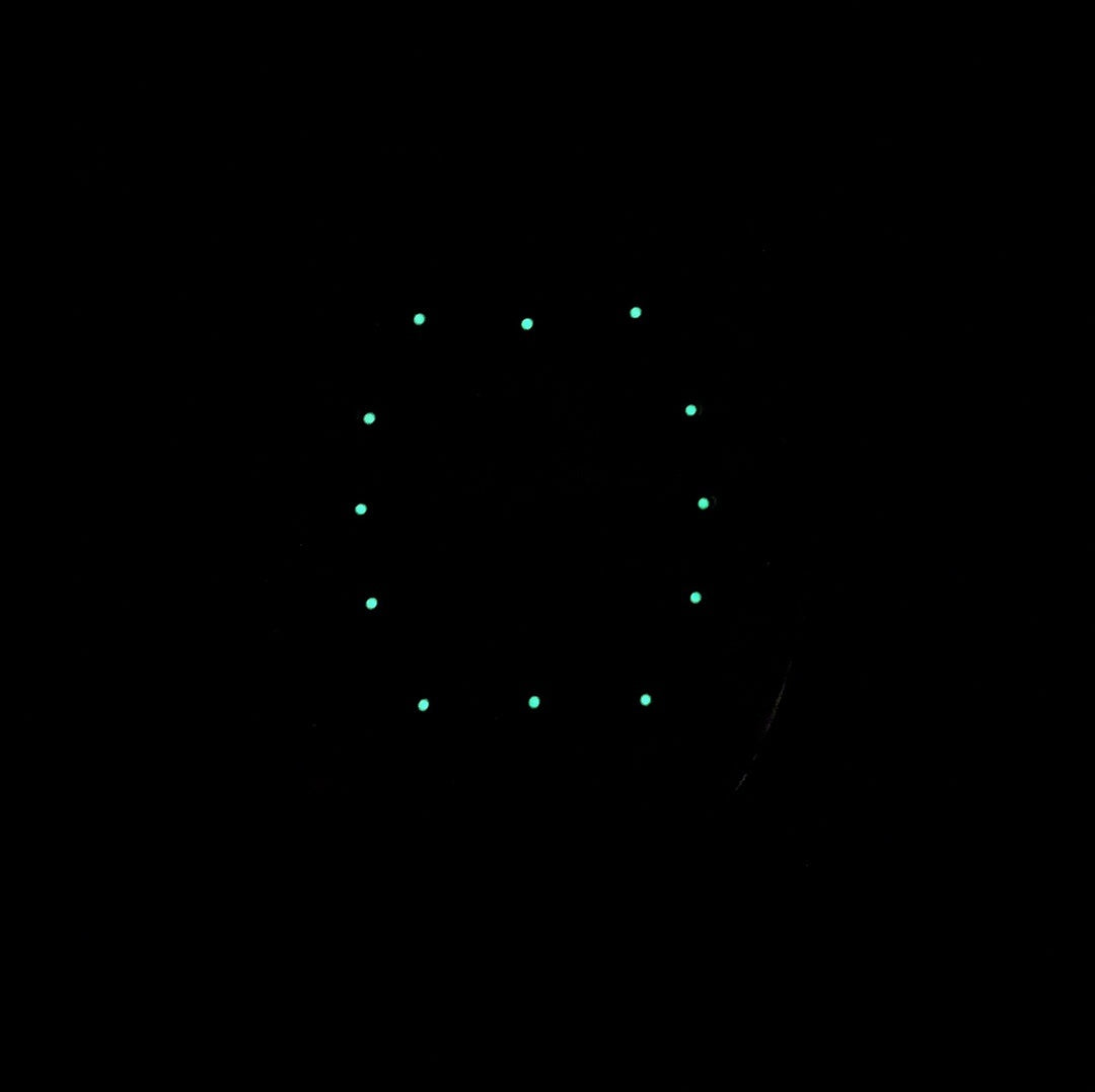 Dark watch dial with luminous minute markers and skeleton movement visible