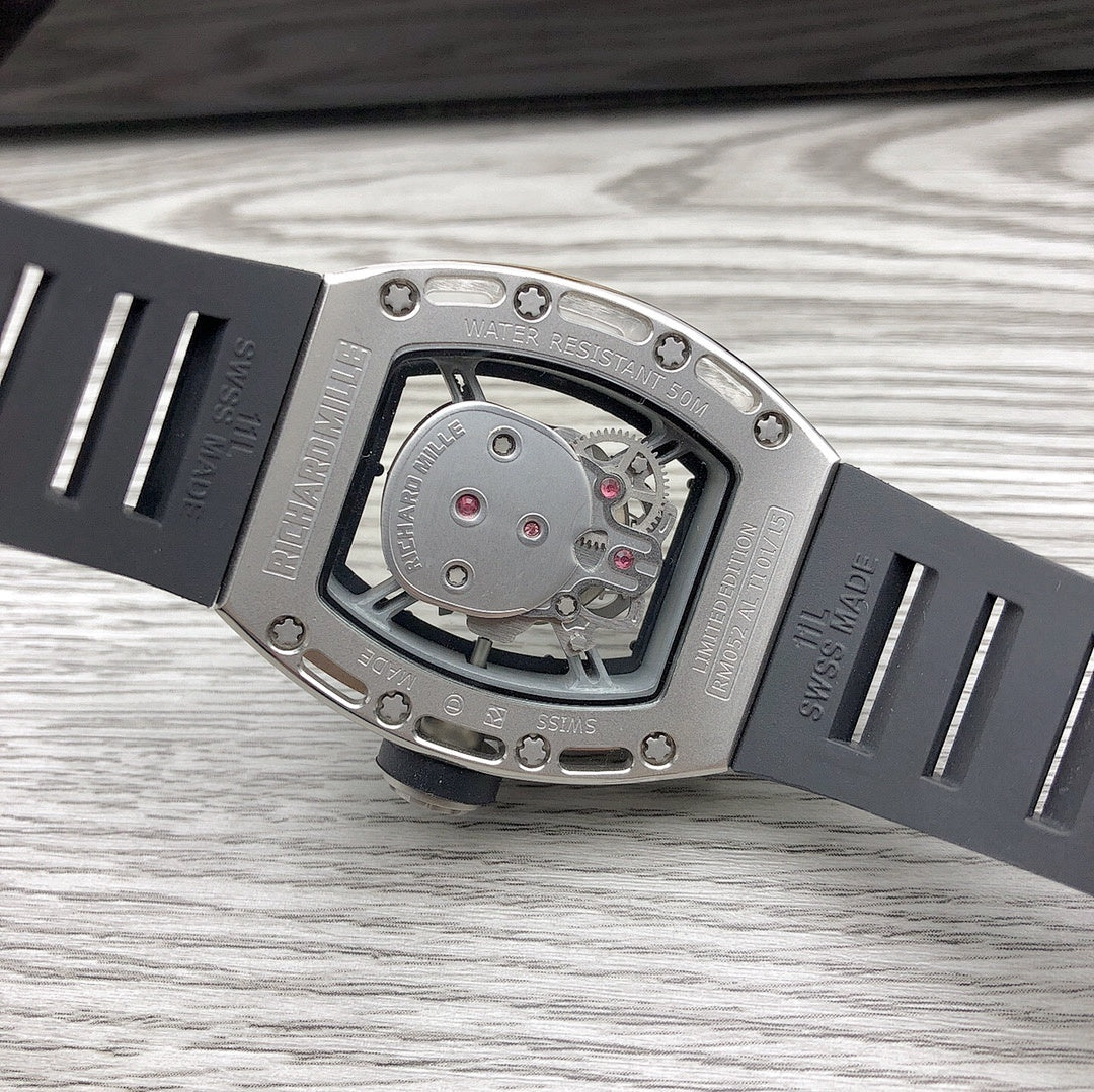Angle view of skeleton watch with silver case and black strap, detailed dial window