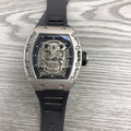 Silver-toned skeleton watch with black rubber strap, exposed gears under glass