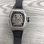 Silver-toned skeleton watch with black rubber strap, exposed gears under glass