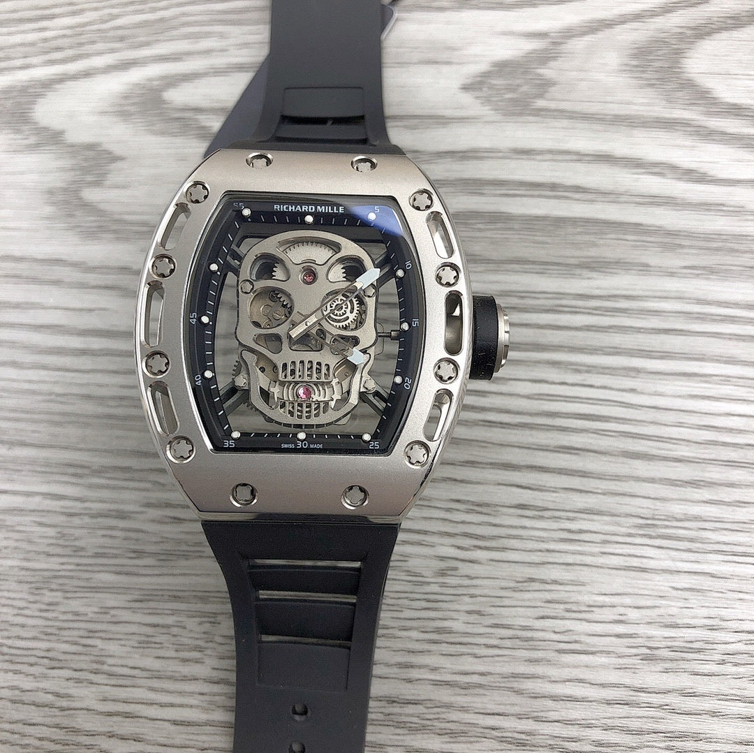Silver-toned skeleton watch with black rubber strap, exposed gears under glass