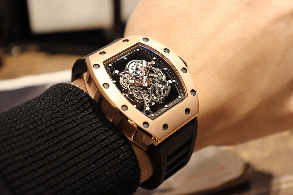 Gold-toned case watch with black rubber strap, angled view of skeleton dial and crown