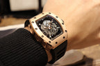 Gold-toned case watch with black rubber strap, angled view of skeleton dial and crown