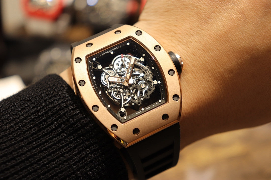 Gold-toned case watch with black rubber strap, close view of skeleton dial on wrist