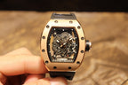 Gold-toned case watch with black rubber strap, front view of exposed skeleton movement