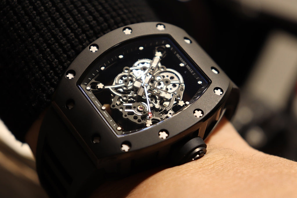 Black skeleton wristwatch with open dial and studded bezel on wrist