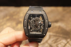 Black skeleton wristwatch on hand, square dial showing mechanical movement