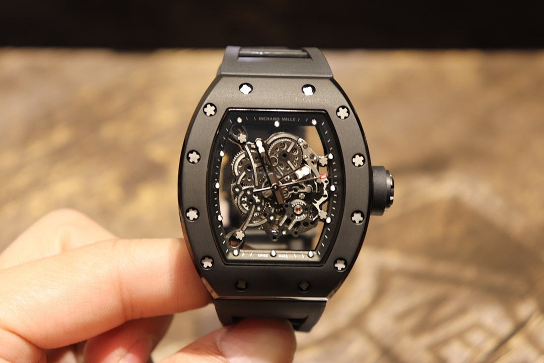 Black skeleton wristwatch on hand, square dial showing mechanical movement