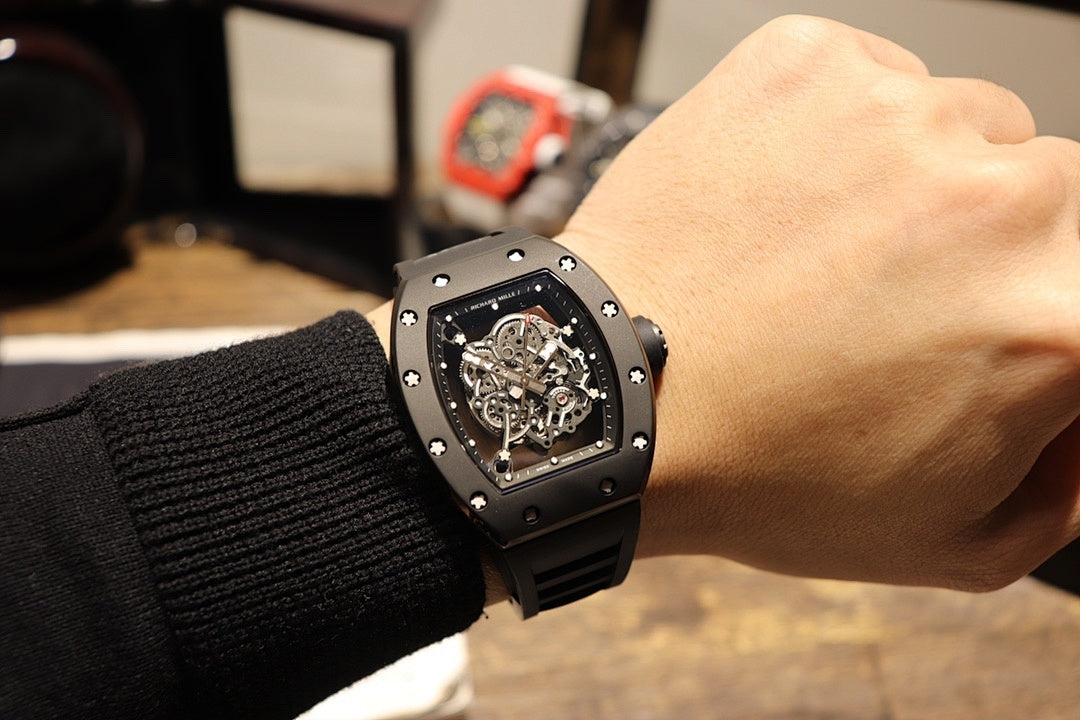 Black skeleton wristwatch on wrist, square bezel with exposed gears