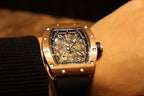 Rose gold-tone luxury wristwatch with skeleton dial and black rubber strap