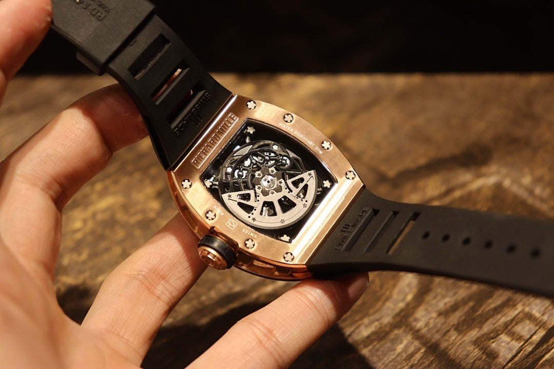 Rose gold-tone wristwatch underside view with skeleton mechanism, black rubber strap
