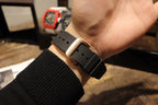 Black rubber watch strap with metal buckle and adjustment holes, on wrist