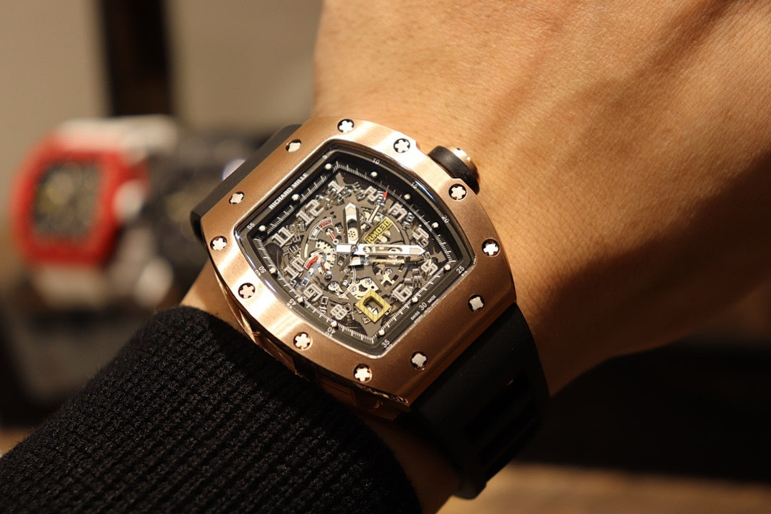 Rose gold-tone skeleton wristwatch with black rubber strap on wrist, front view