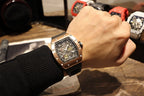Rose gold-tone wristwatch on wrist with skeleton dial and black rubber strap