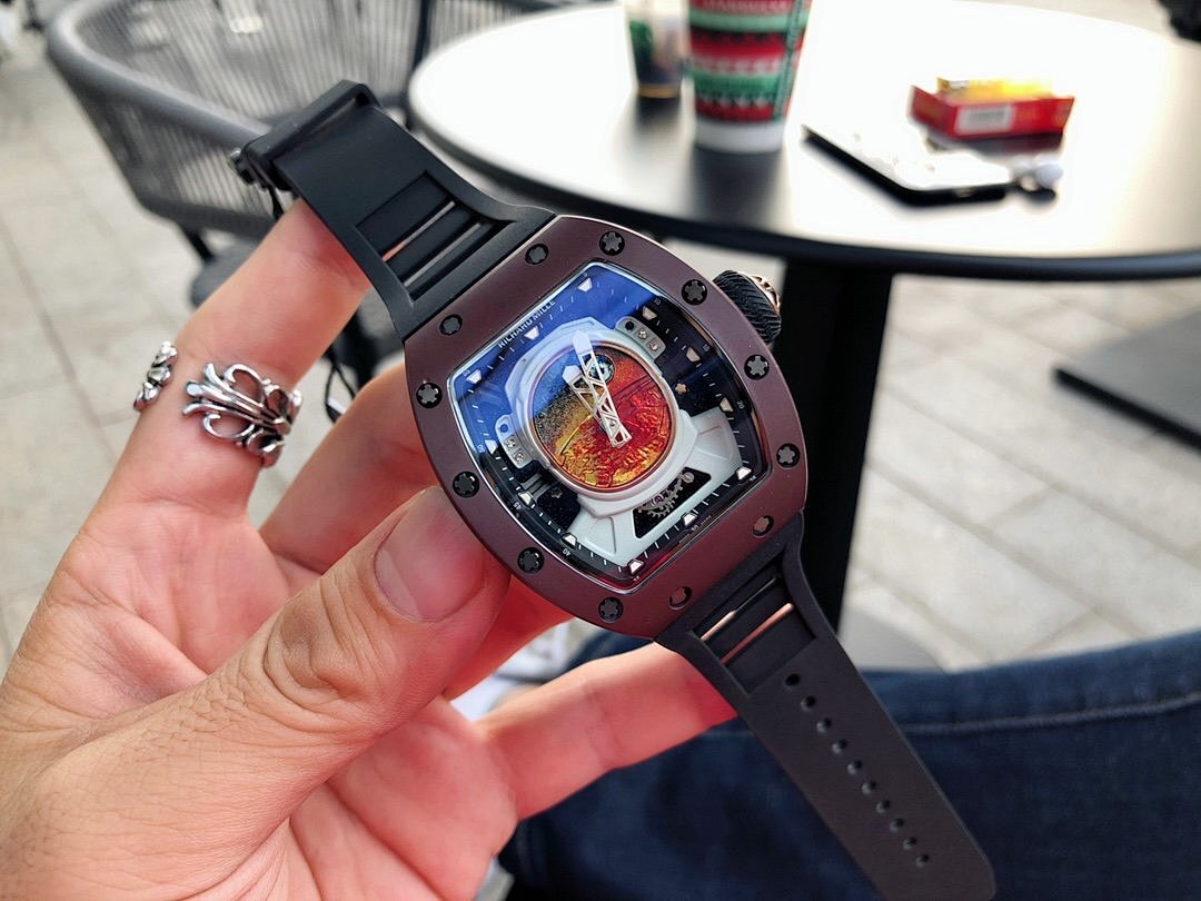 Richard Mille timepiece on hand, burgundy case and black strap, blue skeleton dial